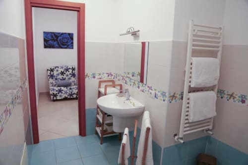 Moderno bagno del B&B The Flower Garden a Castellammare di Stabia con lavabo bianco, porta asciugamani e dettagli di piastrelle colorate