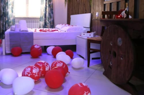 Magnolia Suite al The Flower Garden con romantici palloncini rossi e bianchi che decorano il pavimento e il letto con vista sulla città