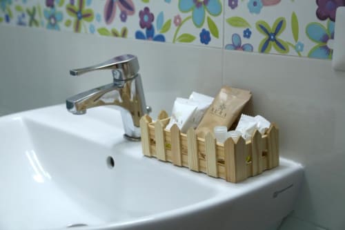 Organizzatore in legno con articoli da toilette e amenità offerte nel bagno del The Flower Garden B&B, Castellammare di