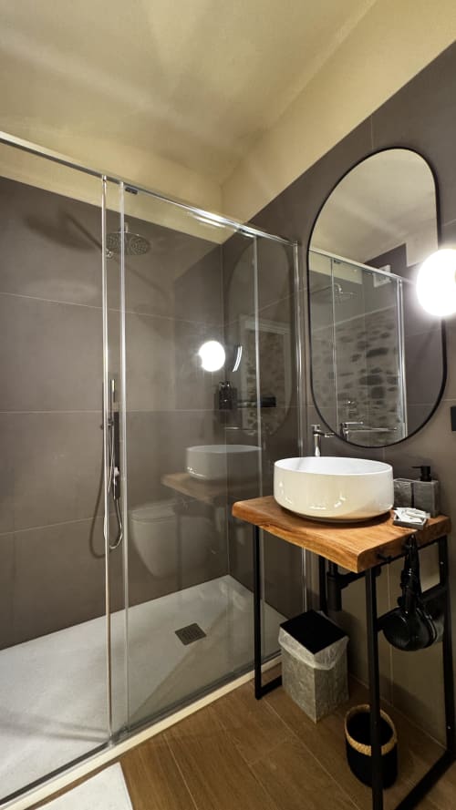 Modern bathroom in Nervia room at Talking Stones Group, Dolceacqua with glass shower, vessel sink, and heated mirror lighting
