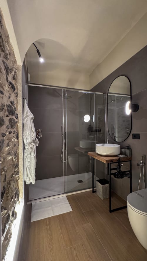 Modern bathroom in Nervia room at Talking Stones Group bnb, Dolceacqua, featuring walk-in shower, vessel sink, and heated