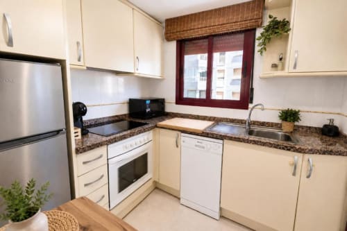 Cocina moderna en Apartamento Aloha, Calpe con gabinetes color crema, encimeras de granito y electrodomésticos de acero inoxidable