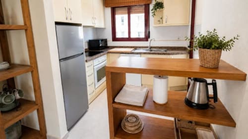 Cocina moderna en Apartamento Aloha, Calpe con isla de madera, electrodomésticos de acero inoxidable y vistas al mar