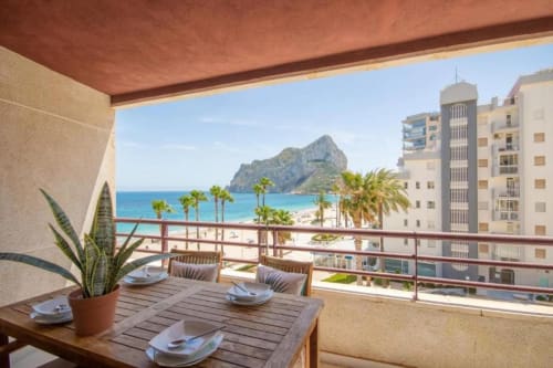 Terraza del apartamento Aloha en Calpe con vistas al mar, mesa de comedor, palmeras y el Peñón de Ifach de fondo