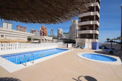 Zona de piscina en azotea del Aloha Calpe con piscinas rectangular y ovalada, tumbonas, vistas al mar y paisaje costero.