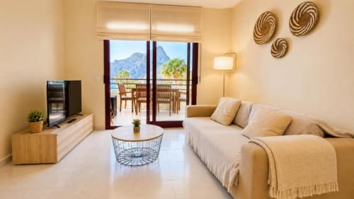 Luminoso apartamento Aloha en Calpe con sofá beige, terraza con vistas al mar y a las montañas