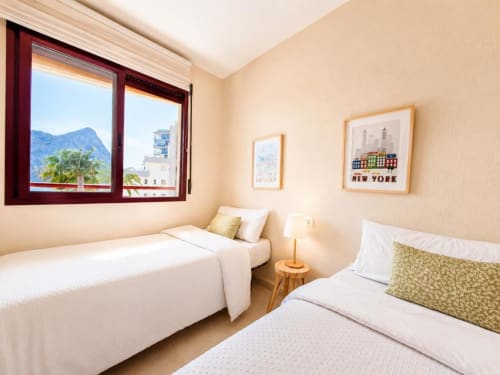 Luminoso dormitorio doble en Aloha Apartment, Calpe con vistas al mar y montaña, ropa de cama moderna y decoración neoyorquina