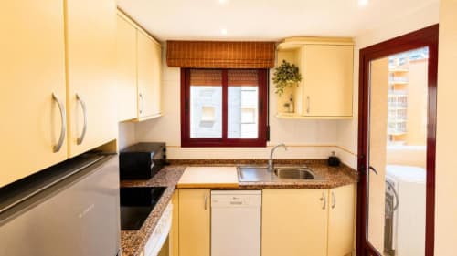 Cocina moderna en apartamento Aloha de Aloha Calpe, Calpe con muebles color crema, encimeras de granito y ventanas con vistas al mar