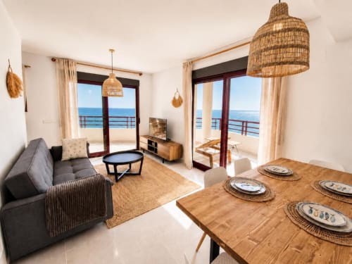Sala de estar del apartamento dúplex Aloha Calpe con vistas al mar, mesa de comedor, sofá cómodo y terraza con vistas