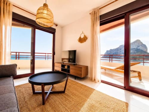 Sala de estar de apartamento dúplex en Aloha Calpe con vistas al mar, mobiliario moderno, TV de pantalla plana y balcón con vistas