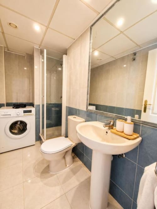 Baño moderno en apartamento dúplex Aloha Calpe con inodoro, lavamanos, ducha y lavadora