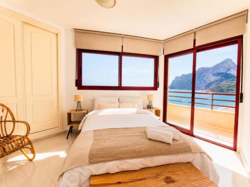 Luminoso dormitorio con vistas al mar en el dúplex Aloha Calpe, Calpe. Montaña y playa visibles desde las puertas de la terraza.