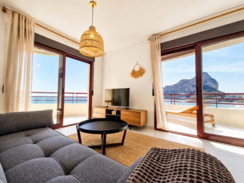 Luminoso dúplex en Calpe con vistas al mar, mobiliario moderno y vistas de montaña desde amplias puertas de balcón