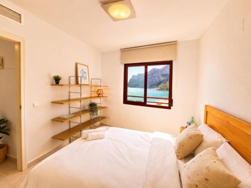Dormitorio luminoso en dúplex Aloha Calpe con vista al mar, ventanas a las montañas de Calpe y aguas turquesas, madera