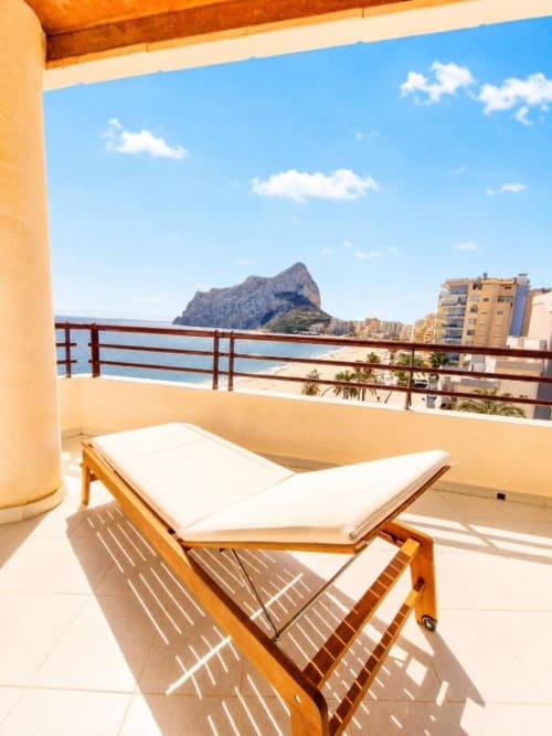 Tumbona de madera en terraza soleada de Aloha Calpe, con vistas al Peñón de Ifach y el Mar Mediterráneo