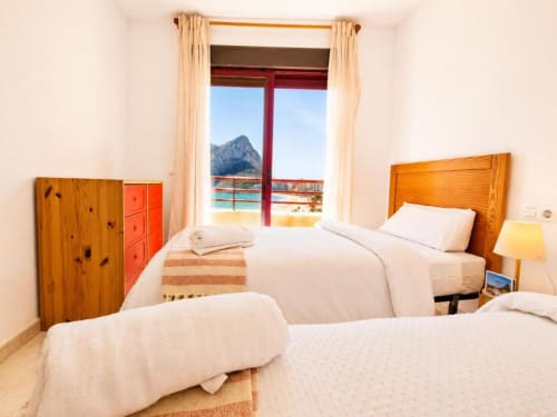 Luminoso dormitorio dúplex en Aloha Calpe con camas gemelas, muebles de madera y balcón con vistas al mar y montaña de Calpe, España
