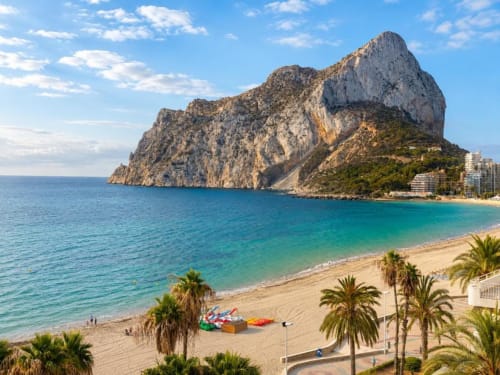 Playa de Calpe con el icónico Peñón de Ifach, mar Mediterráneo turquesa, orilla arenosa con palmeras