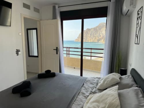 Moderno dormitorio en Calpe con vistas al mar, cama doble, balcón con vistas a la costa rocosa y Mediterráneo en Aloha Calpe