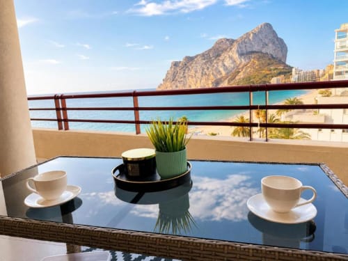 Balcón con tazas de café con vistas al mar Mediterráneo turquesa y el Peñón de Ifach en Calpe