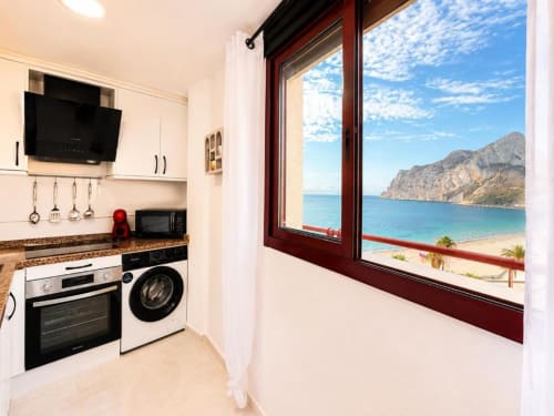 Cocina moderna en apartamento de Calpe con vistas al mar, playa y acantilados a través de gran ventanal