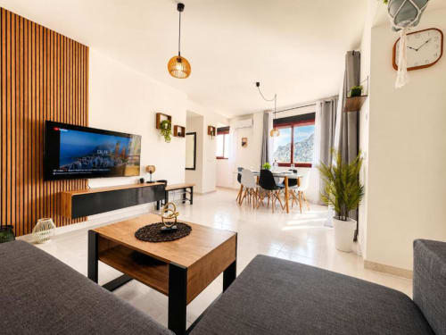 Sala de estar del apartamento Modern Duplex II en Aloha Calpe con pared de madera, TV de pantalla plana, comedor y vistas al mar