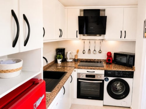 Cocina moderna en el Apartamento Duplex II de Aloha Calpe con encimeras de granito, armarios blancos, horno, lavadora y