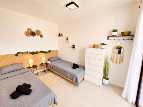 Luminoso dormitorio compartido en dúplex Aloha Calpe con dos camas, cabeceros de madera, almacenaje blanco y vistas a la costa