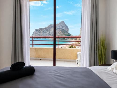 Dormitorio con vistas al mar y el emblemático Peñyal d'Ifach de Calpe, balcón con aguas turquesas mediterráneas, moderno