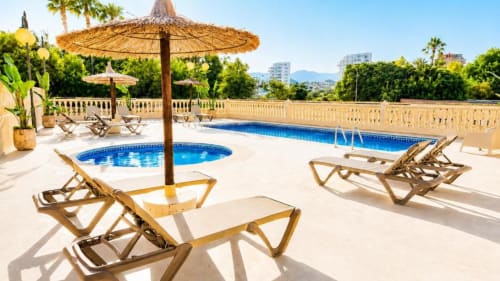 Zona de piscina Aloha Calpe con tumbonas, sombrillas, bañera de hidromasaje y vistas al mar desde la terraza en Calpe, España