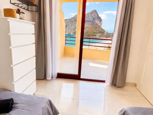 Dormitorio de apartamento en Calpe con balcón con vistas al mar, montaña y playa, muebles modernos y cómoda blanca
