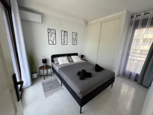 Dormitorio moderno en apartamento Aloha Calpe con cama negra, armario blanco, vistas al mar y decoración minimalista