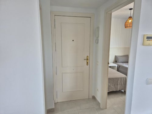 Pasillo moderno en Apartamento Salinas de Aloha Calpe con puertas color crema, luz colgante y acceso a dormitorio