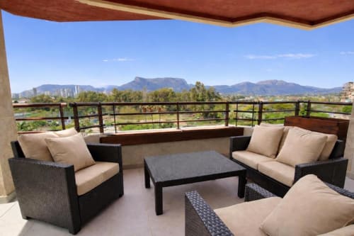 Terraza del apartamento Salinas en Aloha Calpe con muebles de mimbre, vistas a la montaña y Peñyal d'Ifach al fondo