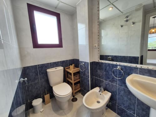 Baño moderno en apartamento Salinas del hotel Aloha Calpe, Calpe, con inodoro blanco, bidé, lavabo y azulejos azul oscuro