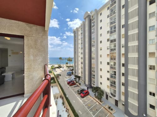 Vista desde el balcón del apartamento frente al mar Aloha Calpe con vistas al Mediterráneo, palmeras y estacionamiento