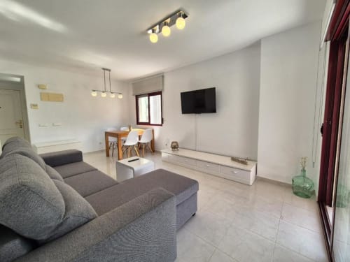 Salón moderno en Apartamento Salinas, Aloha Calpe: sofá gris, TV, zona de comedor y vistas al mar