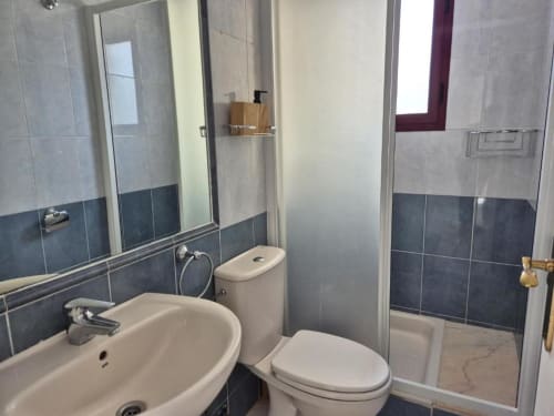 Baño moderno en Apartamento Salinas de Aloha Calpe con lavamanos, inodoro, cabina de ducha y paredes con azulejos azules