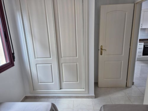 Luminoso pasillo del apartamento Aloha Calpe en Calpe con puertas blancas, suelo de baldosas y acceso a cocina y dormitorio