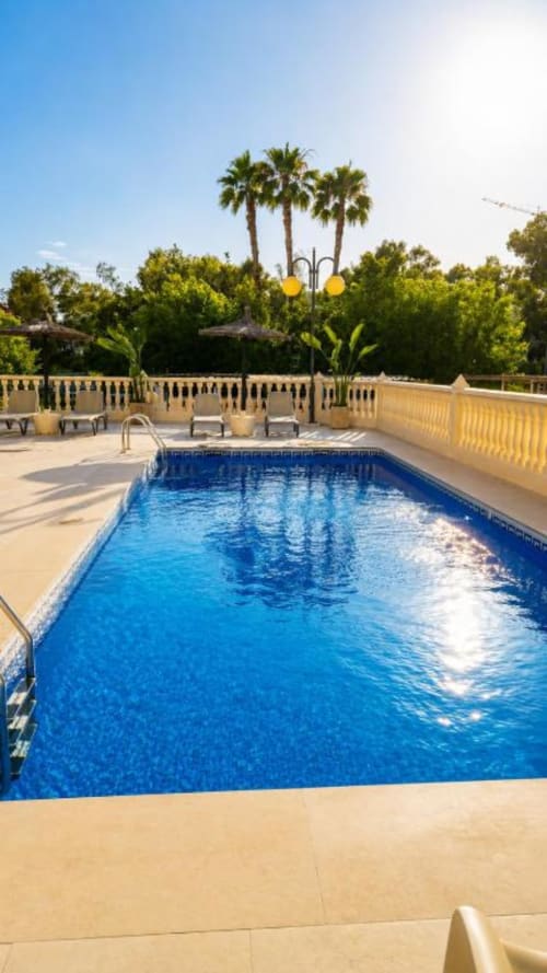 Piscina privada del Apartamento Aloha Calpe Salinas en Calpe con palmeras, tumbonas y terraza soleada