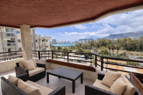 Terraza del apartamento Aloha Calpe Salinas con vistas al mar, tumbonas, mesa y montañas de fondo en Calpe, España.