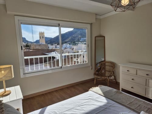 Dormitorio luminoso en apartamento de Calpe con balcón con vistas a la iglesia del casco antiguo, montañas y mar