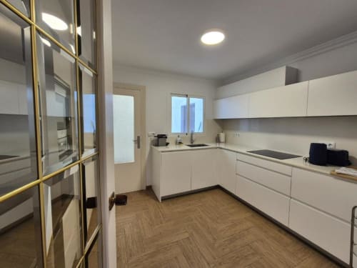 Cocina moderna en apartamento del Casco Antiguo de Aloha Calpe con muebles blancos, suelo de madera y vistas a la ciudad