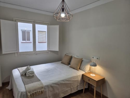 Dormitorio luminoso en apartamento del Casco Antiguo Aloha Calpe, con cama doble, mesilla de madera y vistas al mar