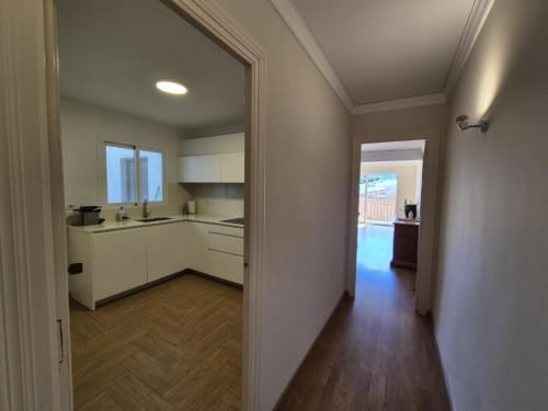 Pasillo con suelo de madera que conduce a la cocina blanca del apartamento Aloha Calpe en el Casco Antiguo de Calpe, España