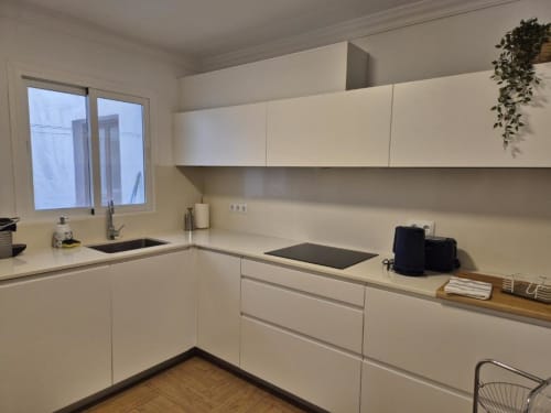 Cocina moderna blanca en apartamento de Aloha Calpe en el casco antiguo de Calpe, con isla con estufa y vistas al mar