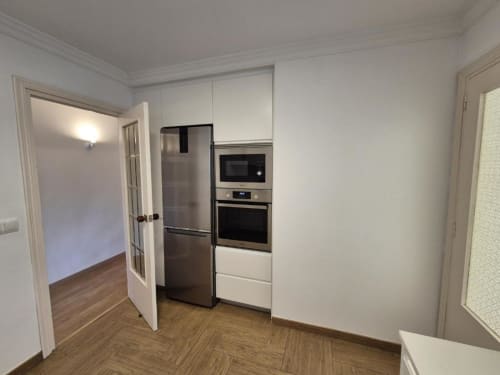Cocina moderna en apartamento del Casco Antiguo de Aloha Calpe con electrodomésticos de acero inoxidable, muebles blancos y pisos de madera