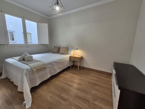 Dormitorio moderno en Aloha Calpe Old Town Apartment, Calpe con cama, mesita de noche, suelo de madera y vistas al mar