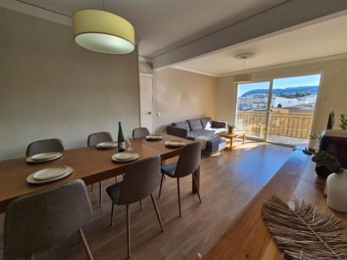 Área de comedor moderno en apartamento Aloha Calpe con vistas al mar a través de puertas de balcón, mesa de madera y sillas contemporáneas