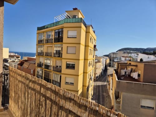 Luminoso edificio de apartamentos en el casco antiguo de Calpe, amarillo intenso, con vistas al mar, arquitectura mediterránea y balcones con vista a la