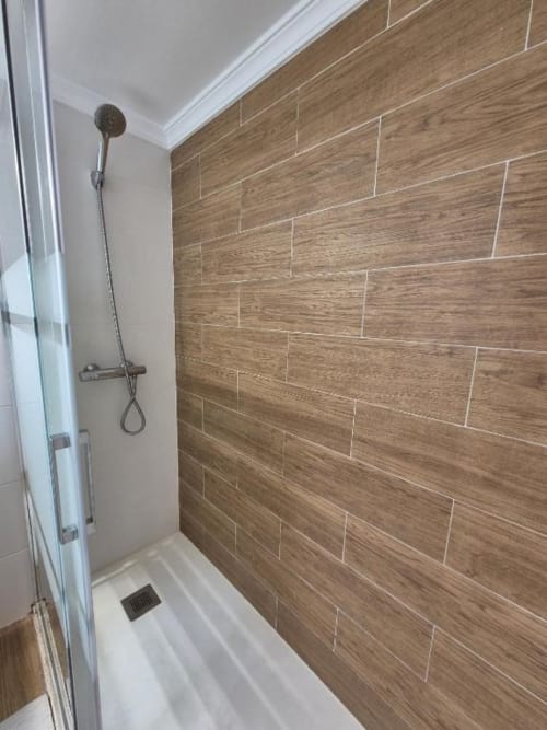 Moderno baño con revestimiento de cerámica efecto madera en el apartamento Aloha Calpe de Calpe
